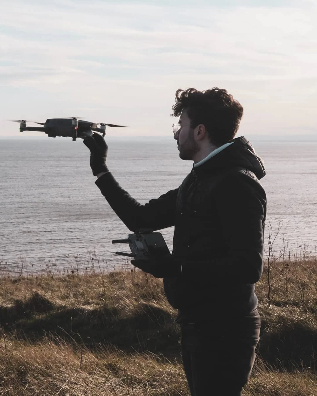 Tiago on a clifftop launching a drone over the sea
